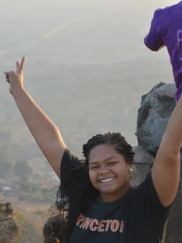 Nicole raises her arms in celebration on a hilltop in Senegal.