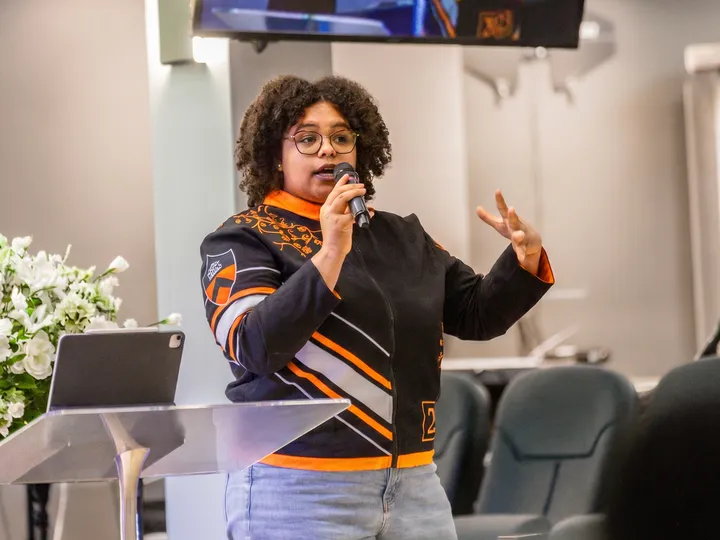 Nicole teaches with a microphone in hand, gesturing as she speaks.
